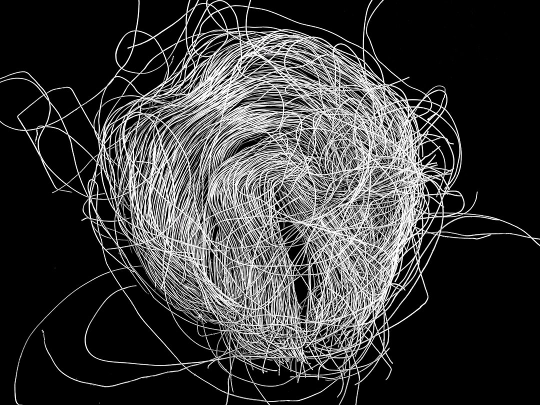 A chaotic arrangement of white lines resembling tangled hair, set against a black background.